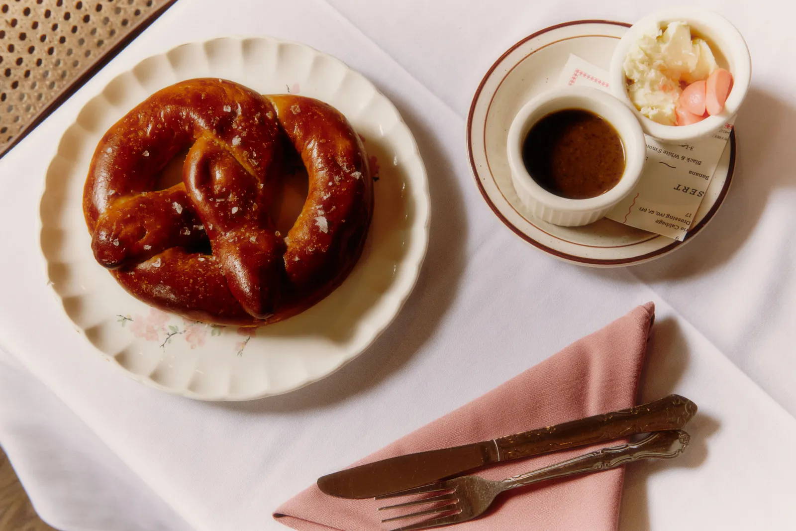 Pretzel on a plate with cutlery.