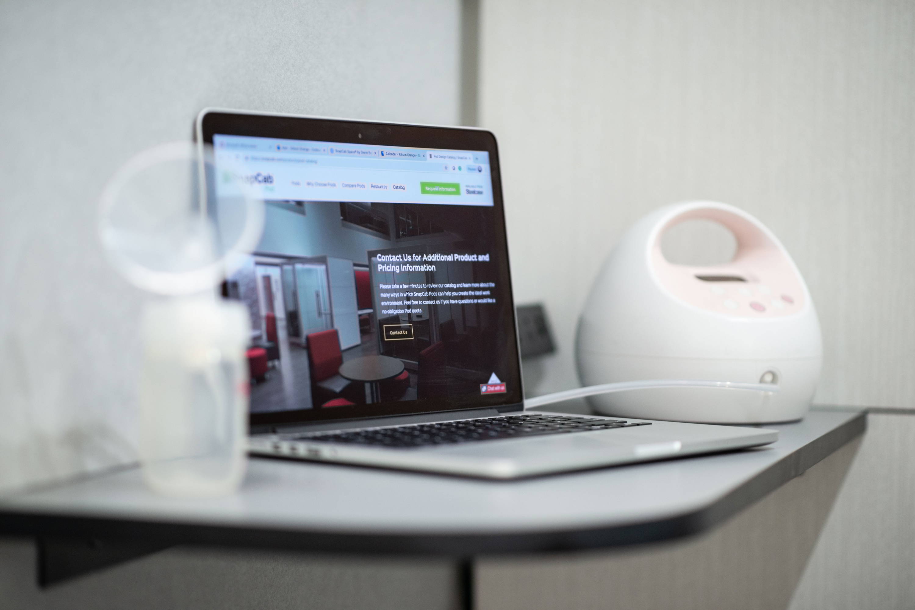 Interior table of lactation pod with laptop and breast pump for mothers in the workplace