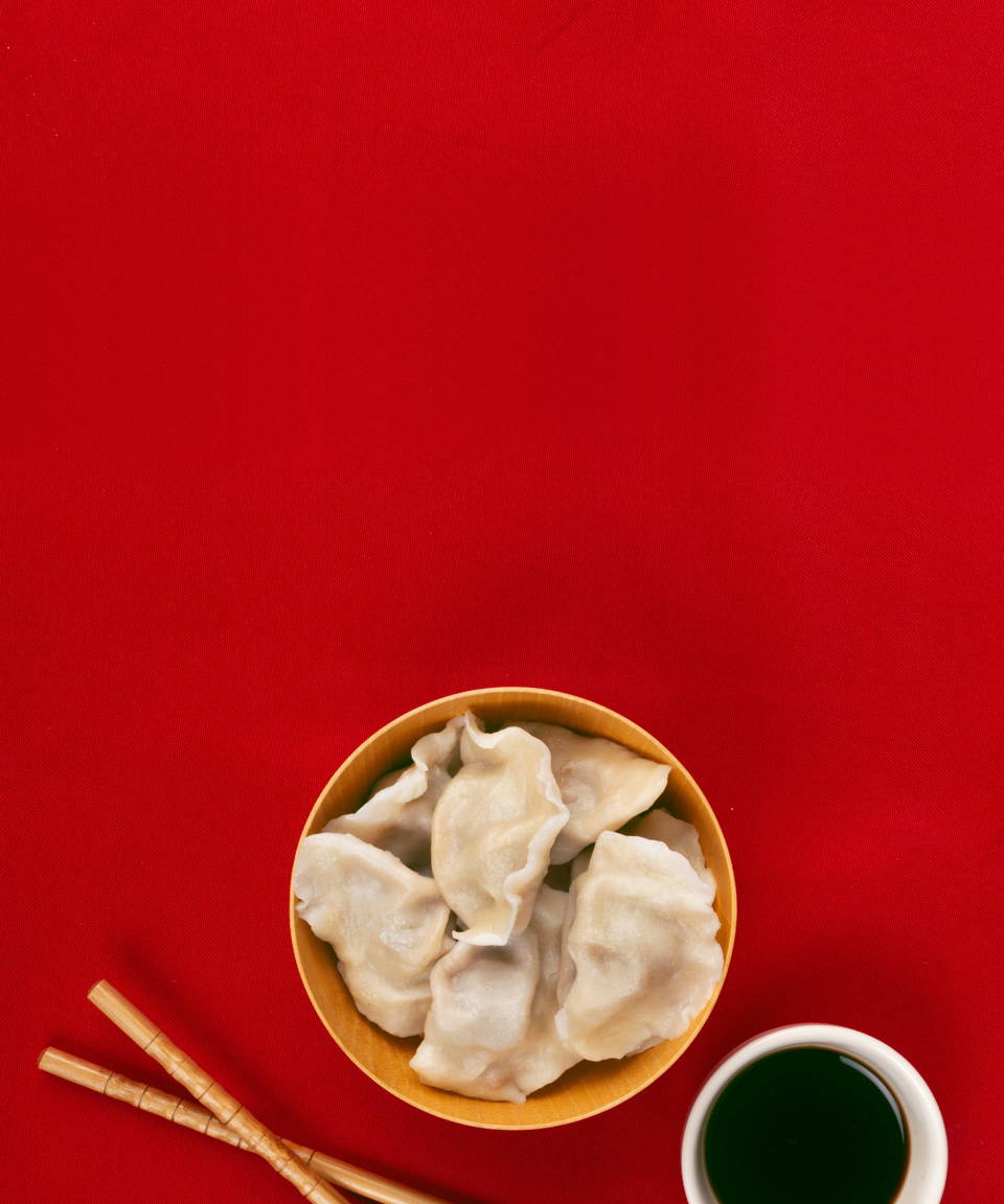 Dumplings in a bowl next to chopsticks and soy sauce for Confetti's Virtual Dumpling Making Class