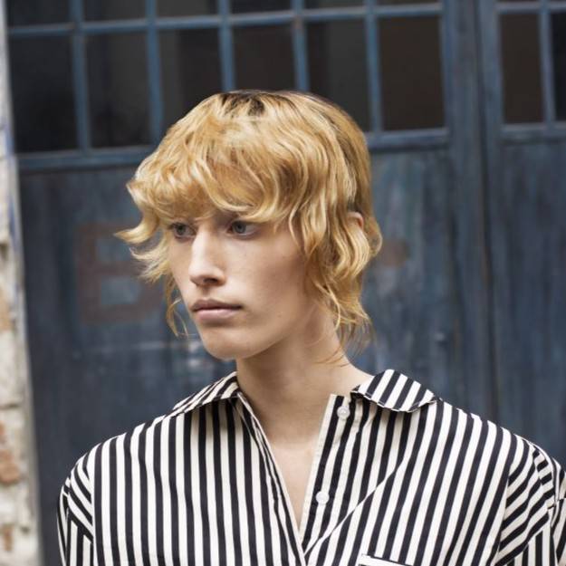 Davines model with blonde, curly hair with bangs