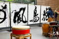A performance-goer for a San Francisco ikebana exhibit admires a huge calligraphy piece, painted in-person by Aoi Yamaguchi’s during the event.
