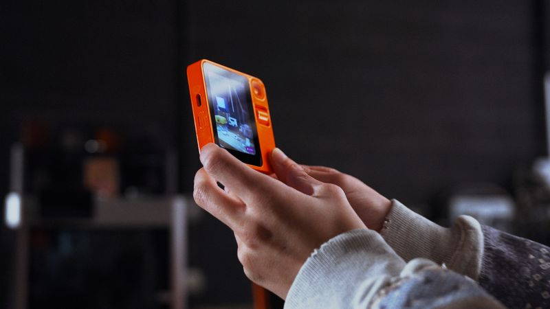Someone holding a device from Rabbit showcasing OS3.