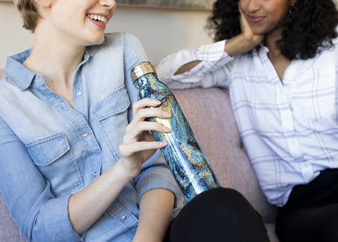 Two people talk while one holds a Swig bottle