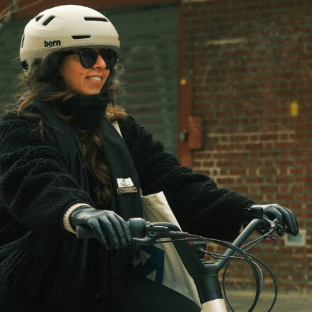a wwoman wearing a white helmet riding an electric city bike