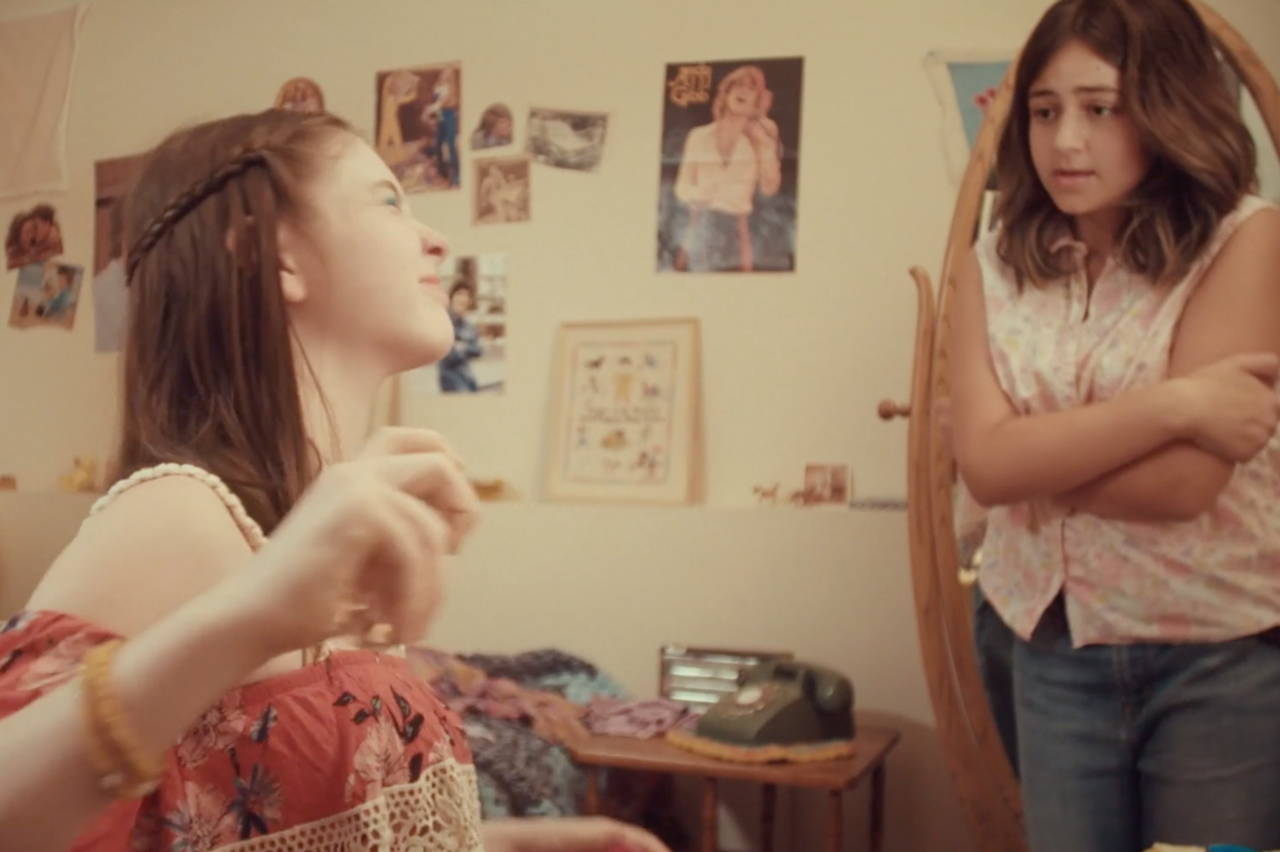 Two teenage girls; one spraying on her Love's Baby Soft cologne.