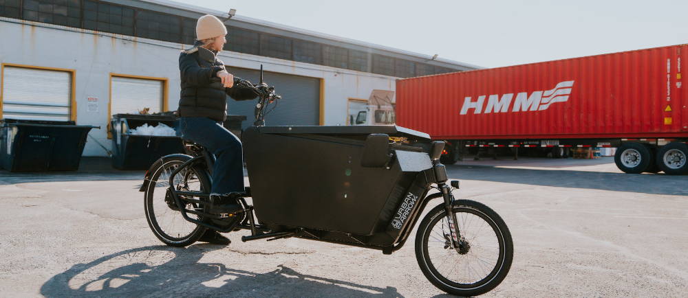Woman on Urban Arrow electric cargo bike in parking lot