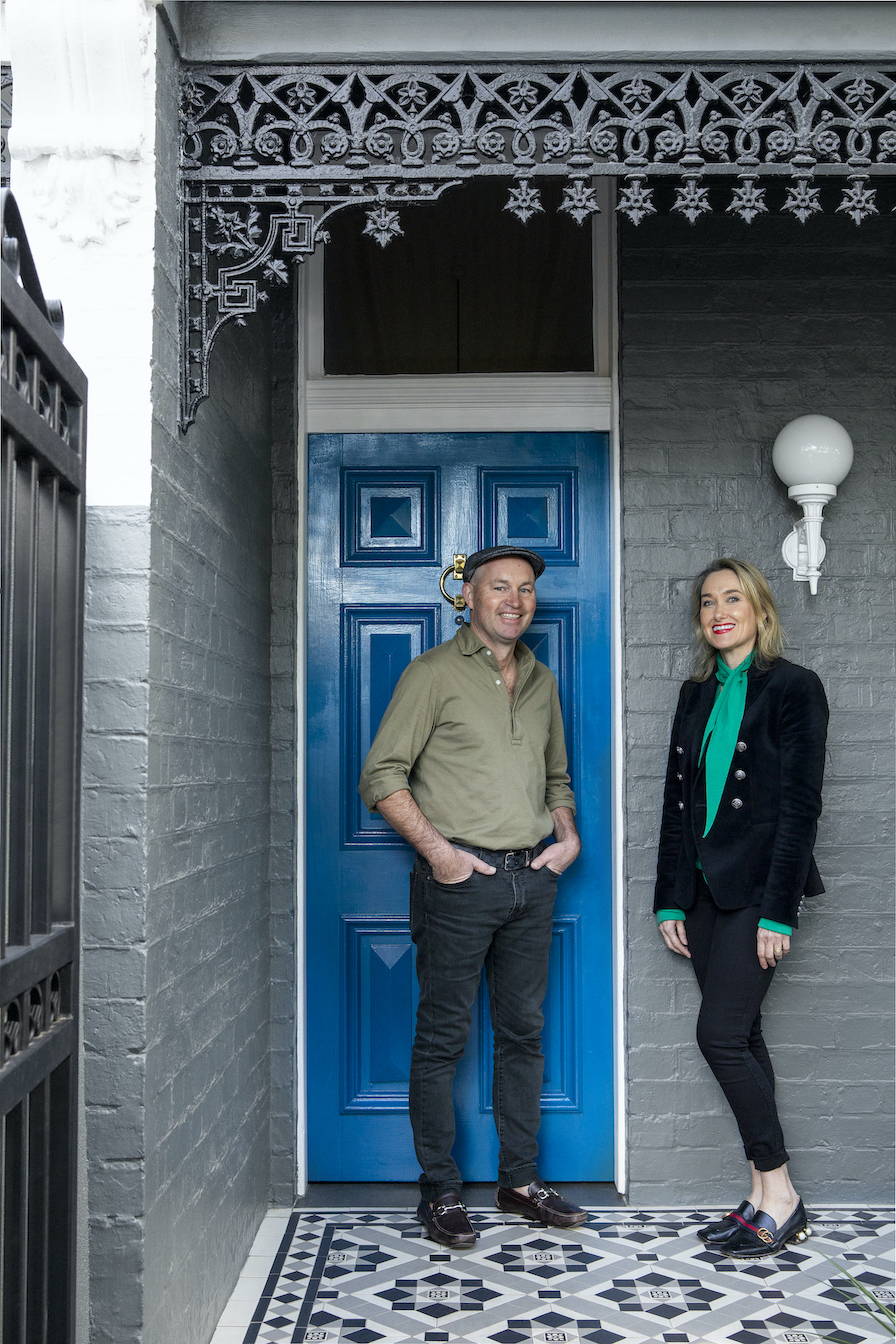 Husband and wife, Matt & Kate standing outside their blue front door