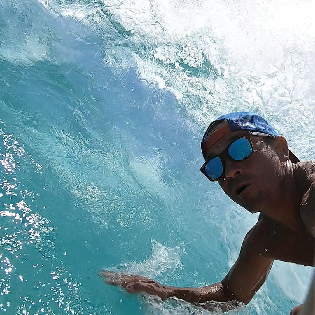 A surfer wears Rheos floating sunglasses inside a barrel.