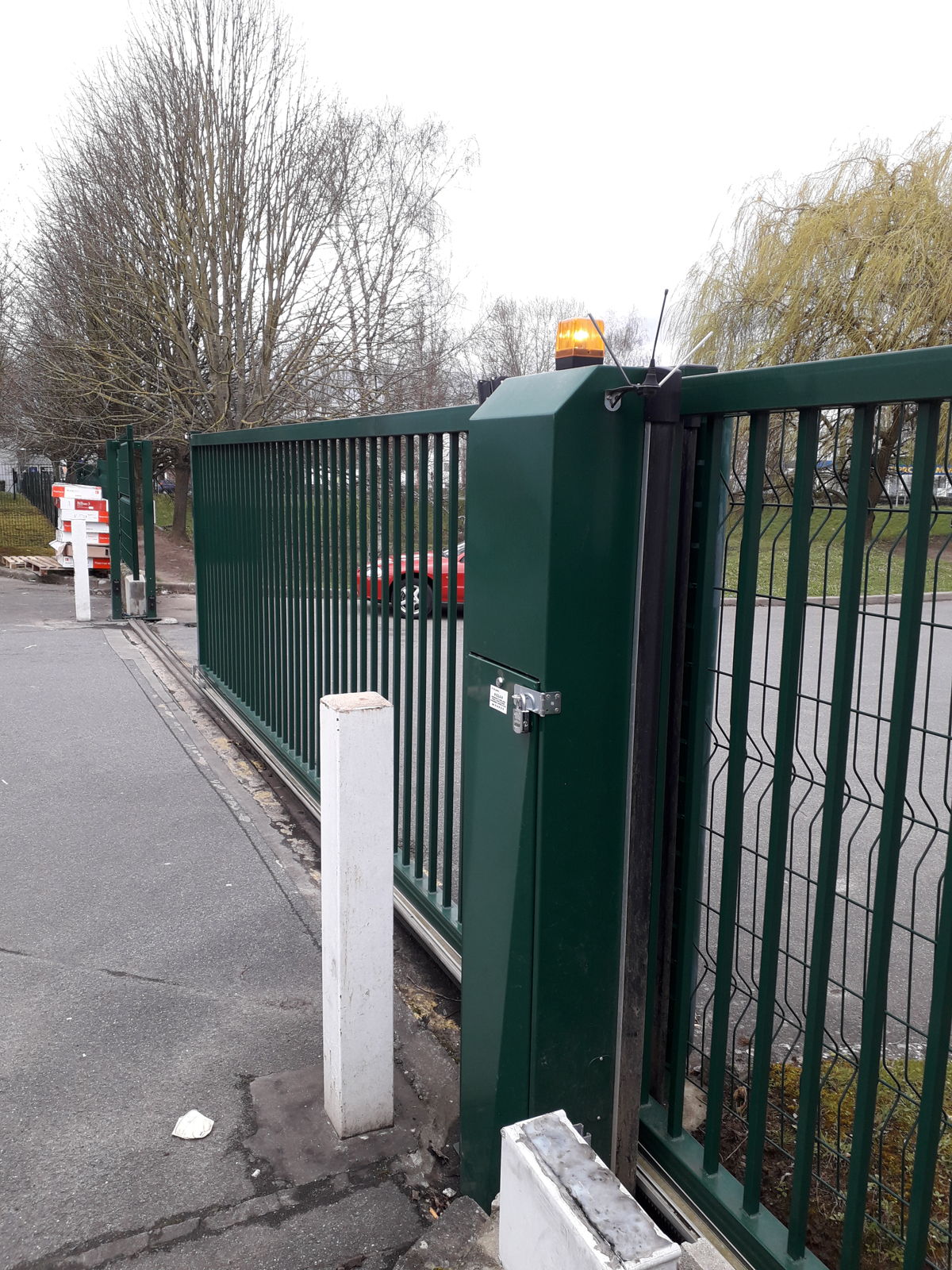 Portail coulissant motorisé avec feu clignotant à l’entrée d’un site professionnel