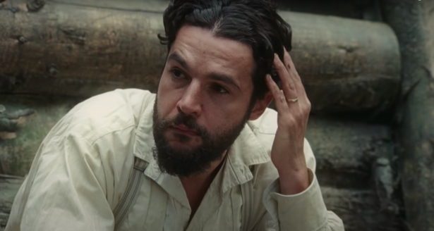 Finney sitting near his house looking to the distance with a concerned expression.