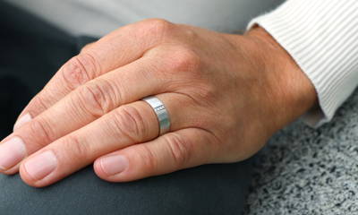 Man's hand with white gold ring with 4 diamonds on the ring finger 