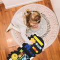 Little girl playing with the Montessori Dino Busy Board. 