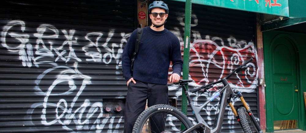 a man standing next to a full suspension electric mountain bike in chinatown