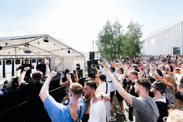 A small crowd listening to a DJ