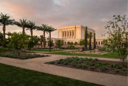 Distant photo of Mesa Temple and grounds. The lawns are green andthe flowerbeds full. Siidewalks criss cross between sections.