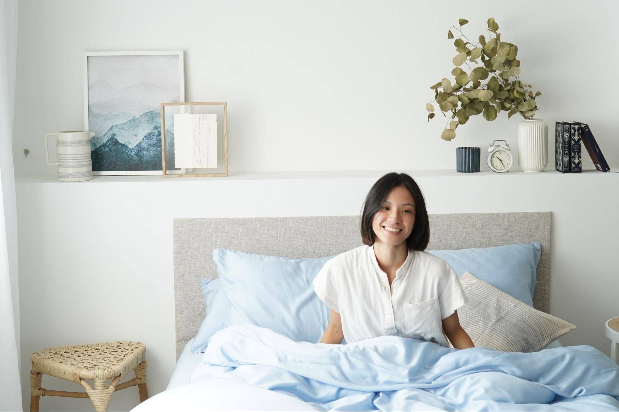 The best bed sheet material to stay cool at night featuring girl sitting on sky blue bed sheets singapore