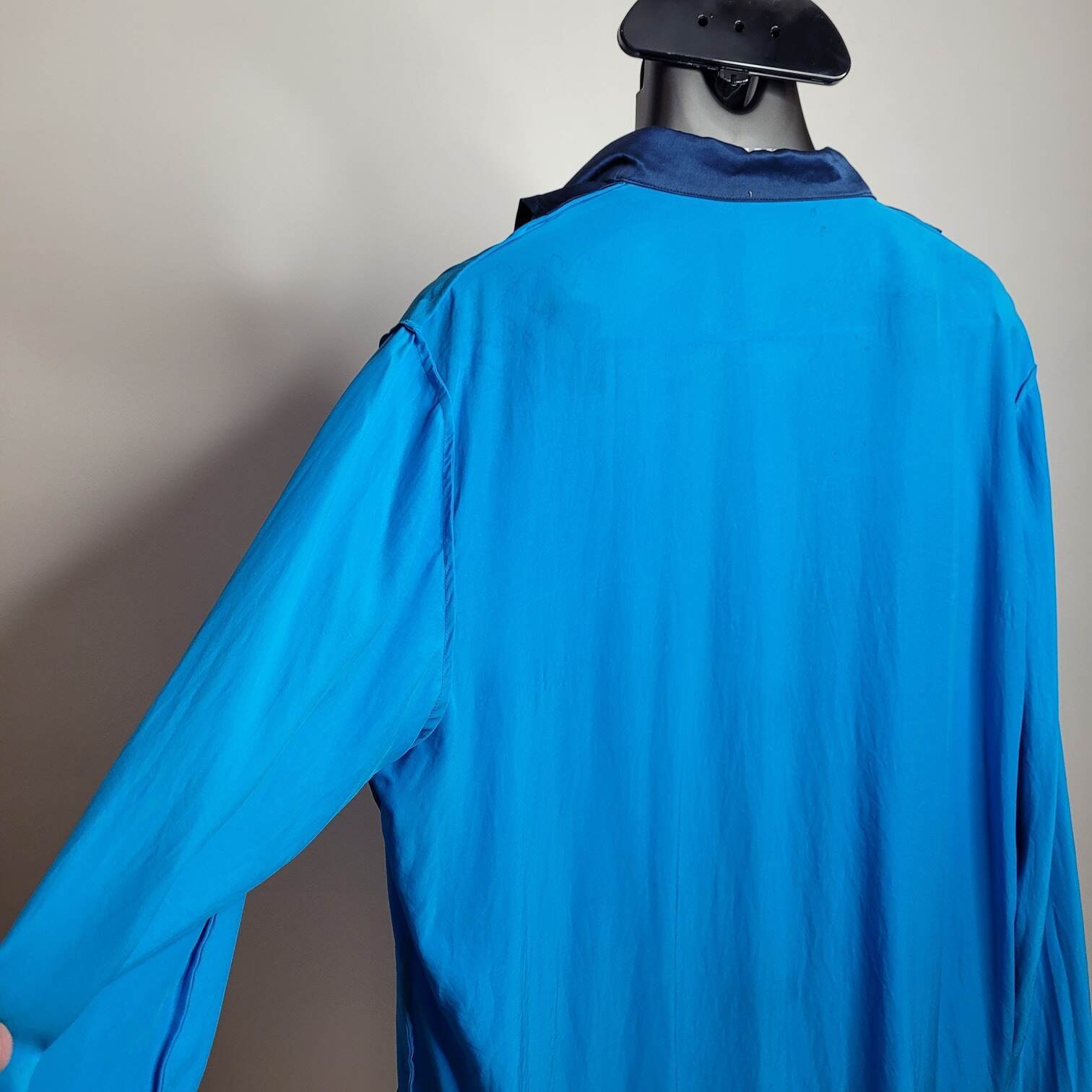 photo of a satin shirt turned inside out and hanging on a hanger on a steamer