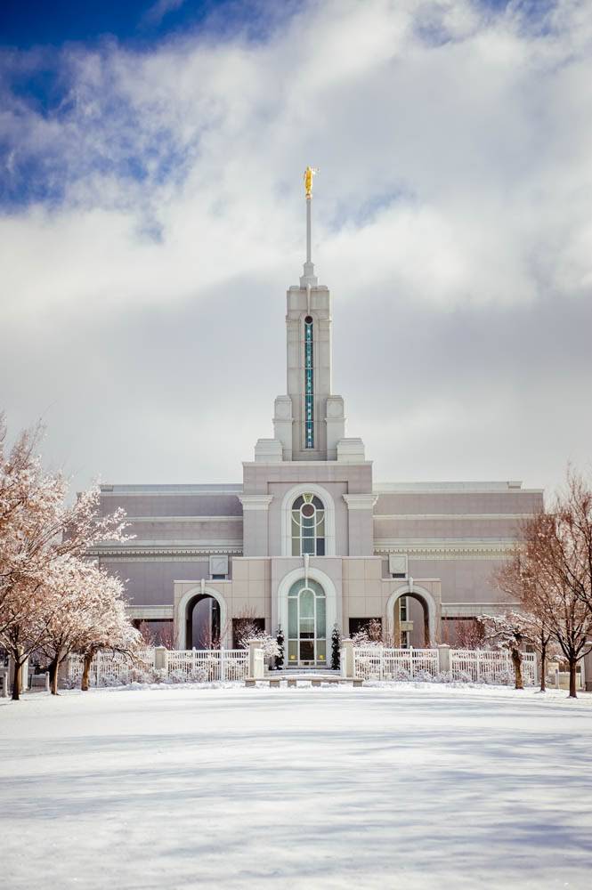 Vertical photo of the Mount Timpanogos Temple with grounds covered in fresh snow.