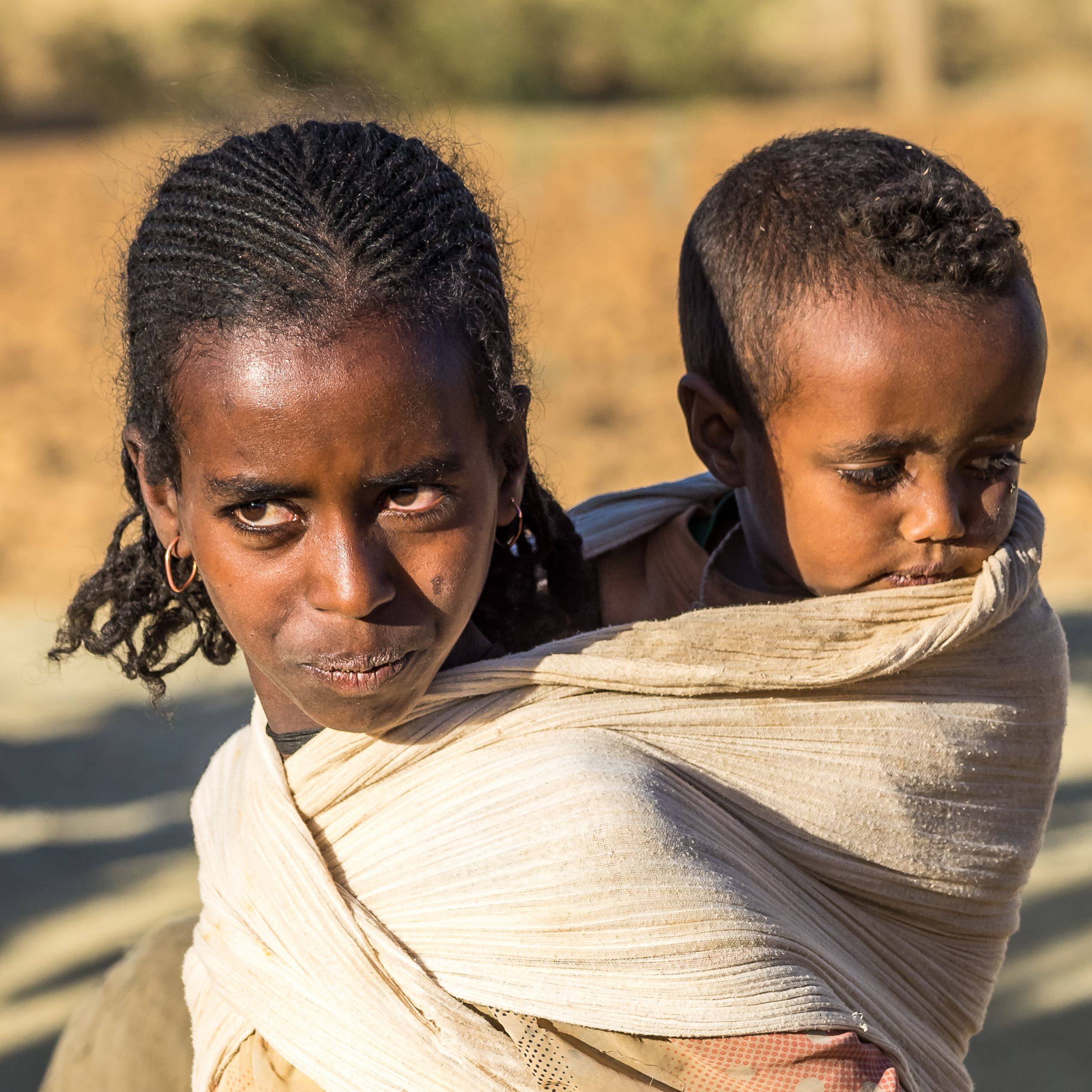 Ethiopian girl with child on her back on roadside in Tigray