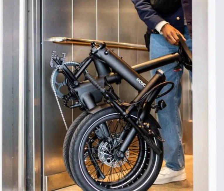 Un homme prend l’ascenseur avec son vélo pliant UTO
