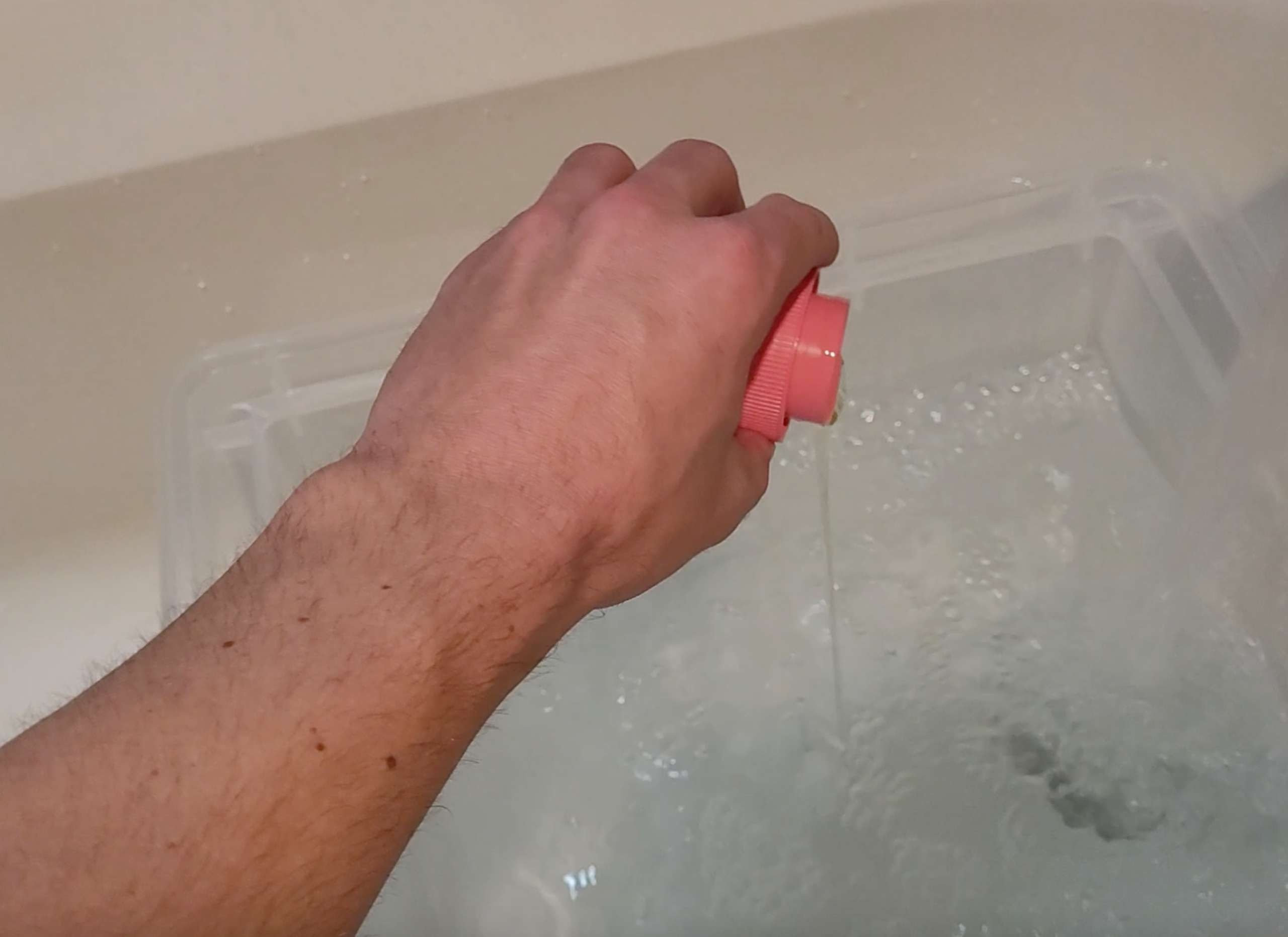 picture of a hand pouring some silk laundry detergent out of a cap and into a basin of water