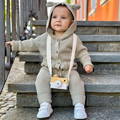 Little boy in a cute outfit with a Montessori Wooden Camera strapped around his neck.