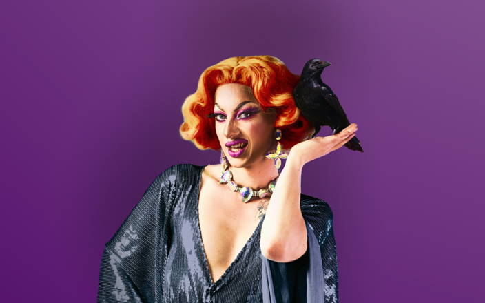 A drag queen striking in a pose wearing a dark glittery gown and holding a black crow for Confetti's Virtual Halloween Bingo Game