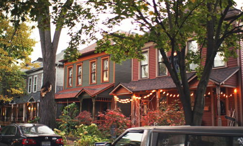Colorful houses with soft lighting create a cozy, inviting street, surrounded by greenery, evoking nostalgia and community.
