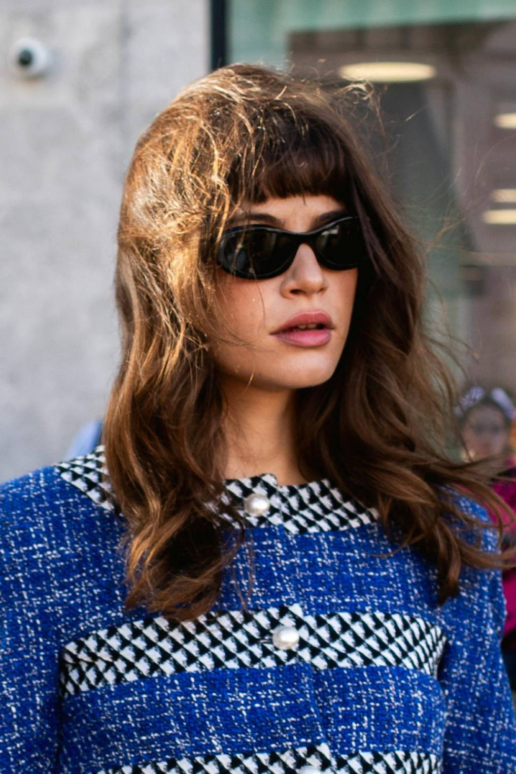 woman with brown hair and bangs wearing sunglasses