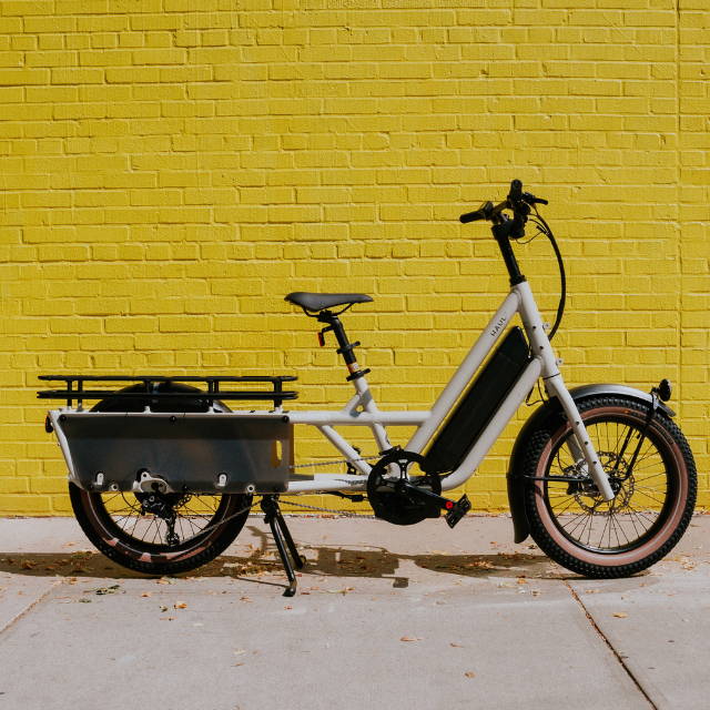 a Specialized Globe Haul elctric cargo bike against a yellow brick wall
