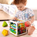 Little boy playing on a bedroom carpet and putting a ball in a Montessori Shape Block. 