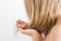 Closeup of blonde woman holding damp hair in her hands