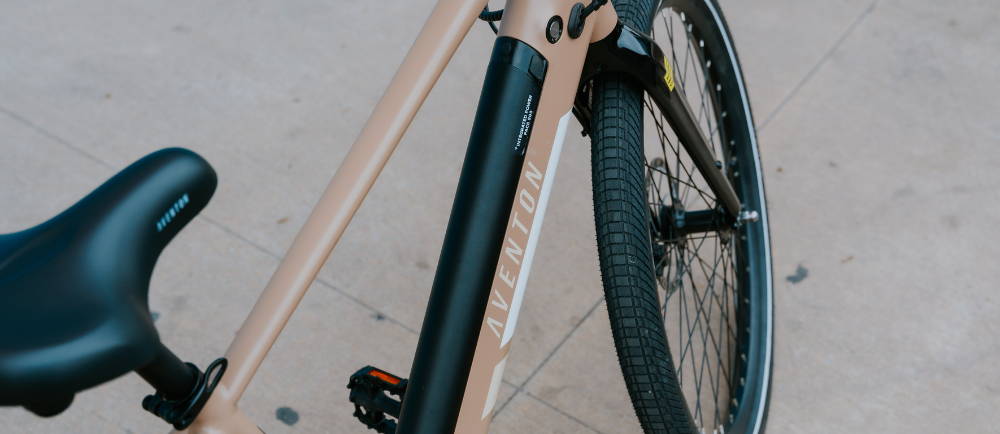 a tan aventon pace electric city bike on grey pavement
