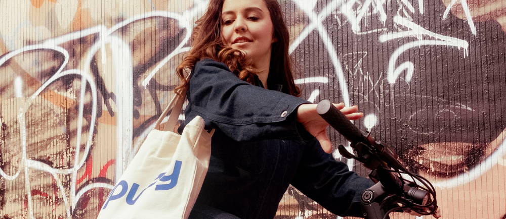 a woman on a bike with a tote bag