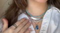 woman in a white button up shirt with stacked necklaces