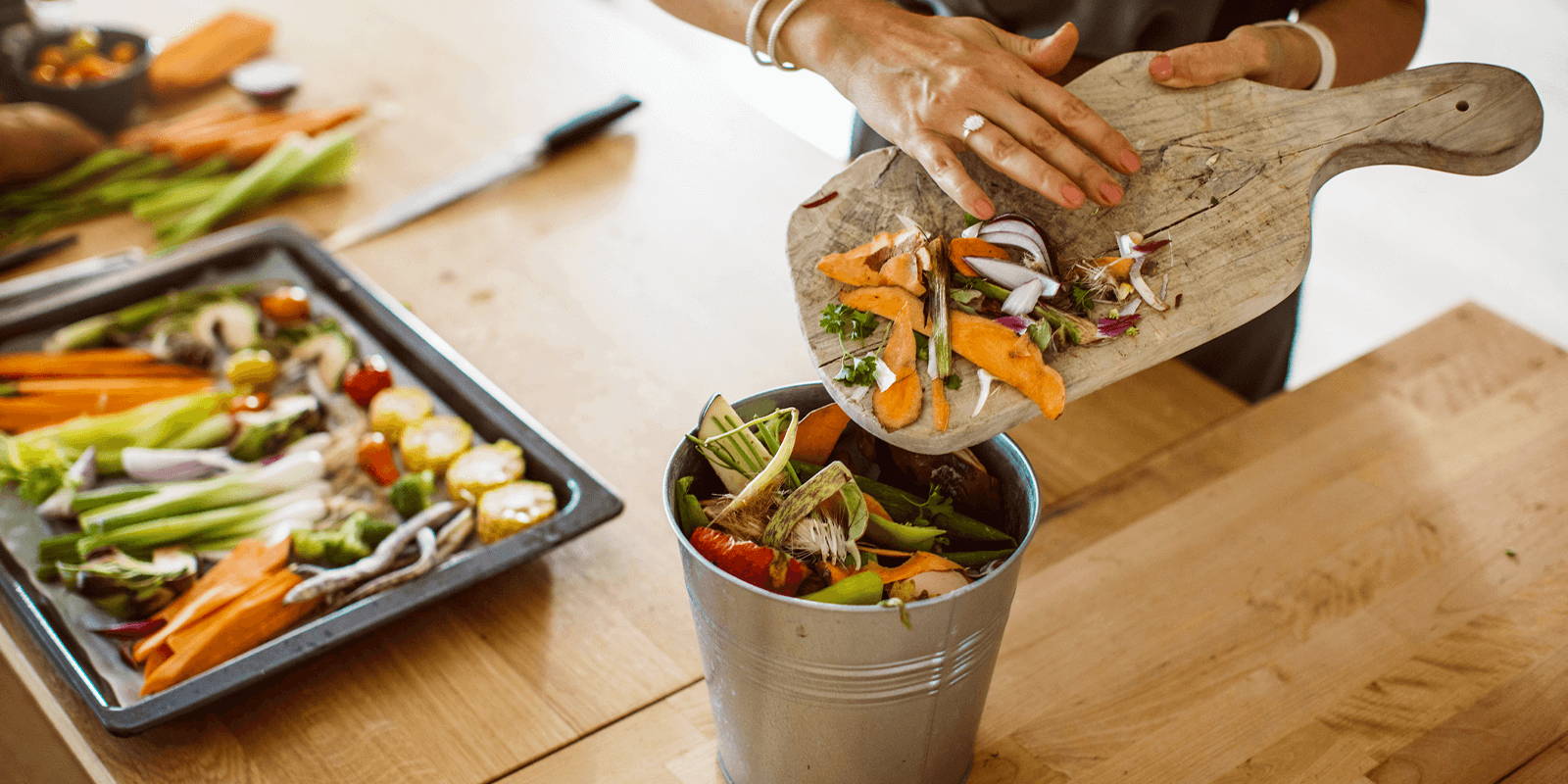 Woman putting vegetables scraps into a bin.