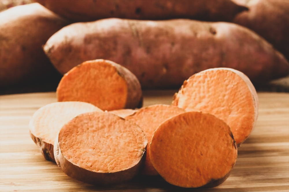 Slice sweet potatoes on wooden cutting board