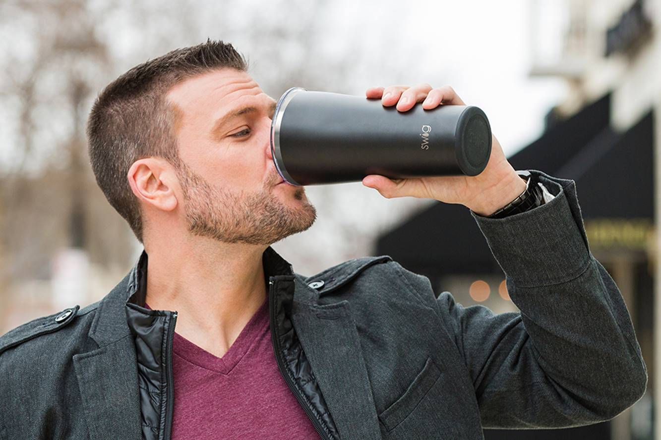 A man drinking from a black Swig tumbler