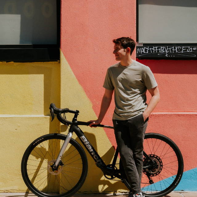 a a man standing next to a Bianchi E-Impulso electric road bike against a multicolored wall