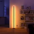 Eine Round Smart Lampe mit einem pinken und gelben Farbübergang neben einer kleinen Couch