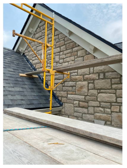 Scaffolding set up beside a gabled stone wall on a historic building, prepared for brick and stone replacement and restoration.