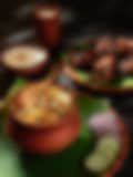Close-up of a traditional Indian chicken biryani dish on a banana leaf, garnished with onions, cucumbers, and yogurt
