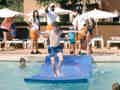 Kinder und Erwachsene am Pool mit blauer Wasserrutsche, beaufsichtigt durch das Personal.