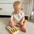 Blonde toddler sitting on the carpet and playing with a Montessori Switch Board.