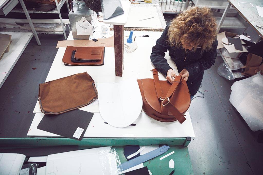 Woman in a factory in Florence assembling an Opus Mind bag using upcycled leather