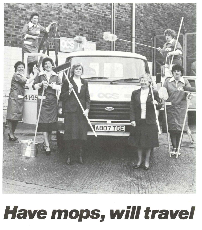 Black and white photo of seven women posing in front of a van labeled OCS. They are holding mops, brooms, and cleaning tools. The text at the bottom reads, Have mops, will travel.