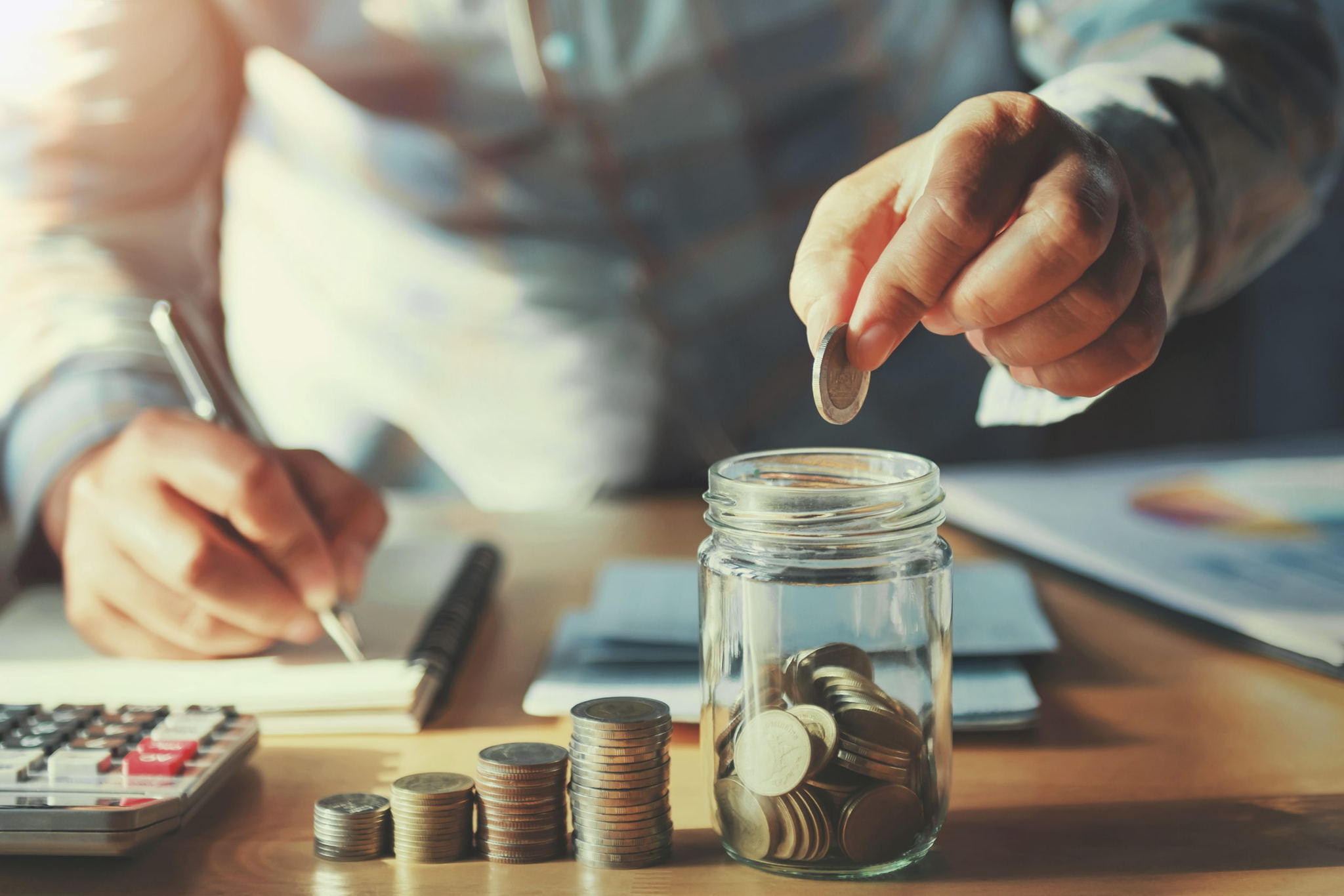 man counting coins and budgeting with calculator