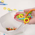 Hand holding colorful wooden circles, sticks, and arches above a storage bag.
