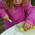 Baby putting a decoration on a birthday cake.