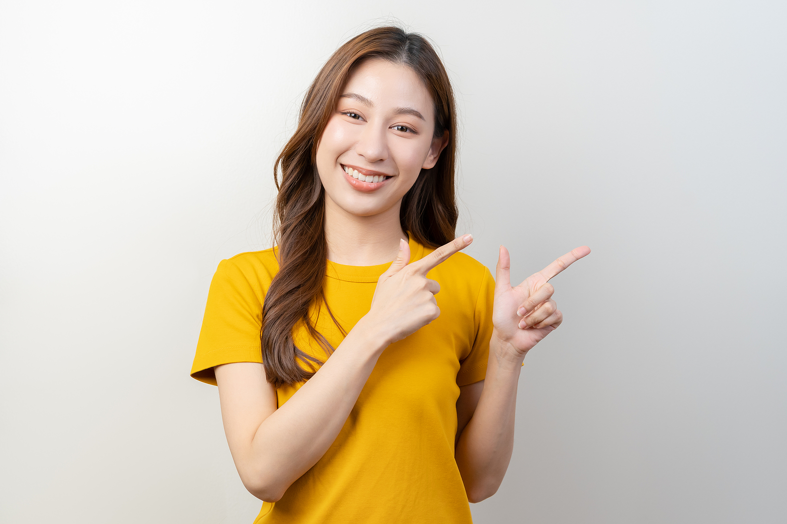 An asian woman smiles while posing with finger guns.